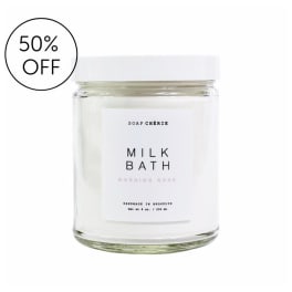Clear glass jar candle with a white lid and label reading Milk Bath