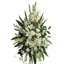 Tall standing spray of white lilies and roses with lush greenery on a metal easel.