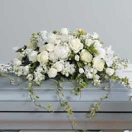 White floral casket spray with trailing greenery