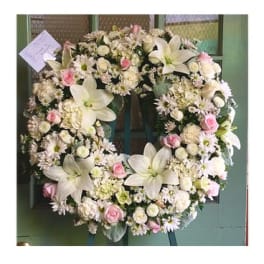 Large white floral wreath with pink roses and lilies