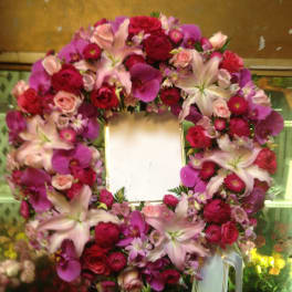 Heart-shaped floral wreath with pink and red flowers around a blank center