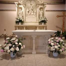 White and pink floral arrangements around a church altar and casket