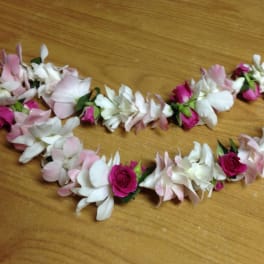 Two floral garlands of pink and white blossoms on a wooden surface