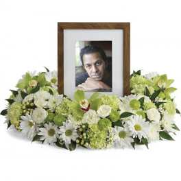Ring of white daisies and green flowers encircling a wooden photo frame for a memorial display
