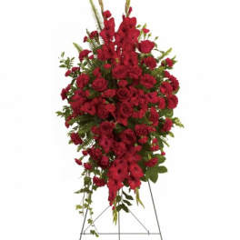 Tall standing spray of red roses and carnations with other red flowers on a metal easel.