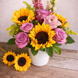 Bouquet of sunflowers and lavender roses in a white vase
