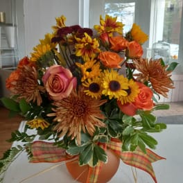 Mixed bouquet of orange and yellow flowers in a round vase