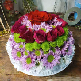 Round bouquet of red roses and lavender daisies on a white plate