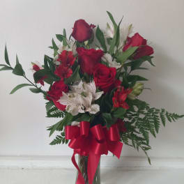 Red roses and white lilies in a glass vase with a red ribbon