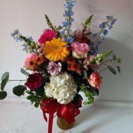 Mixed bouquet in a gold vase with a red ribbon