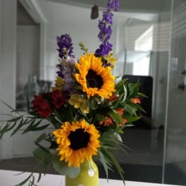 Sunflowers and mixed flowers in a yellow polka-dot vase