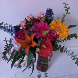 Colorful mixed bouquet in a vase with gerbera daisies, roses, lilies, and anthurium