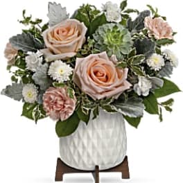 Arrangement of peach roses, carnations, and white daisies in a white vase