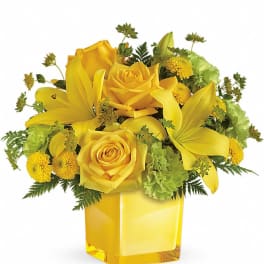 Yellow roses and lilies arranged in a square glass vase