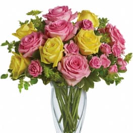 Pink and yellow roses arranged in a clear glass vase
