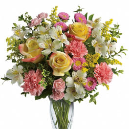 Mixed bouquet of roses, carnations, and white alstroemeria in a glass vase
