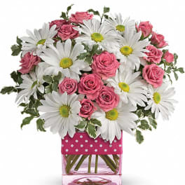 Pink roses and white daisies in a pink glass vase with polka-dot ribbon