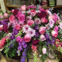 Large arrangement of pink roses and purple flowers on a table