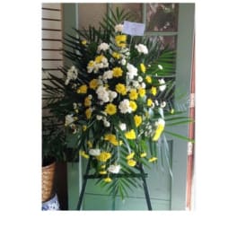 Standing floral spray with yellow and white flowers on an easel