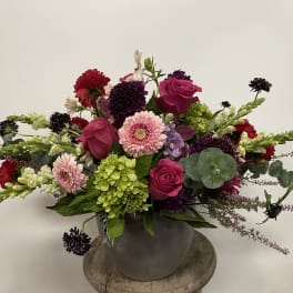 Mixed bouquet of pink roses, gerbera daisies, and green hydrangea in a gray vase