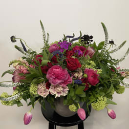 Mixed pink and red floral arrangement in a dark vase