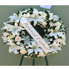 White funeral wreath with lilies and roses on a stand