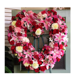 Heart-shaped floral wreath with pink lilies, red roses, and carnations