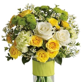 Bouquet of yellow and white roses with green pompon mums in a glass vase