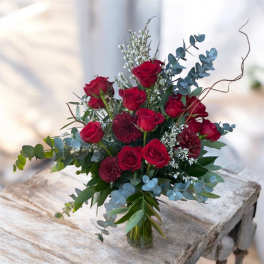 Bouquet of red roses with blue eucalyptus in a glass vase