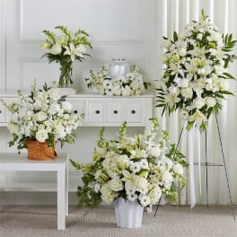 White floral funeral arrangements with lilies and roses in vases and stands