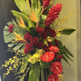 Tall tropical floral spray with red blooms and yellow orchids on a stand