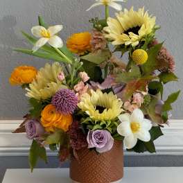 Mixed bouquet of sunflowers, roses, and white daffodils in a textured vase