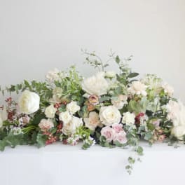 Low floral arrangement with white and blush roses on a white table