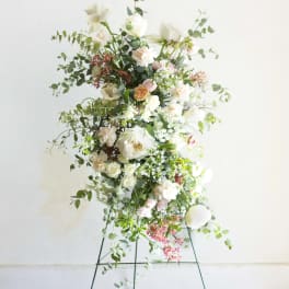 Tall floral arrangement on a metal stand with white and blush blooms