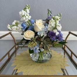 Mixed bouquet of white, blue, and purple flowers in a glass vase