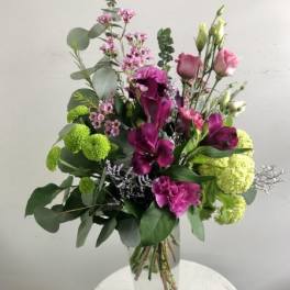 Tall bouquet of purple and pink flowers in a clear glass vase