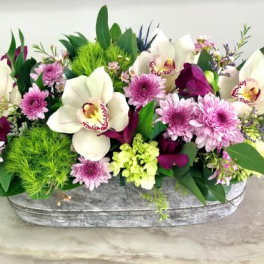 White orchids and pink flowers in a gray container