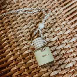 Small perfume bottle hanging from a braided cord on a woven surface
