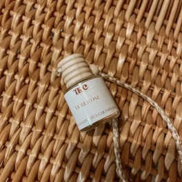 Small hanging car diffuser bottle on a woven surface