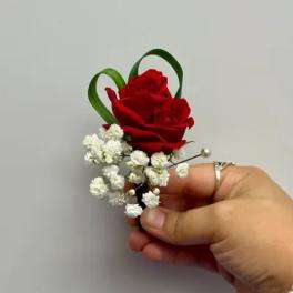 Red rose boutonniere with white baby's breath and green loops