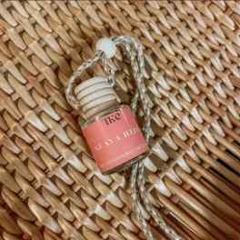 Small glass hanging bottle with a pink label and braided cord
