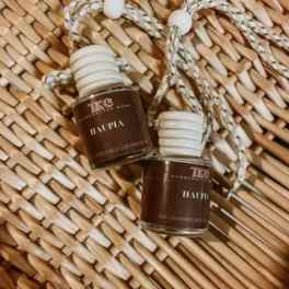 Two small brown glass perfume bottles with braided cords on a woven mat.