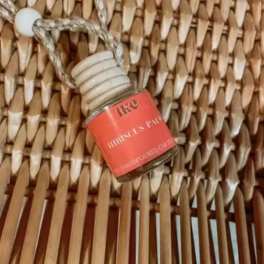 Small perfume bottle with a coral label hanging on a woven surface