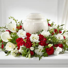 Red roses and white calla lilies arranged around a white urn