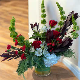 Arrangement of red roses, white flowers, and blue hydrangea in a glass vase