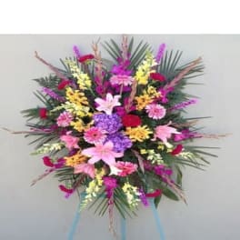 Large standing spray of mixed pink, purple, yellow, and white flowers