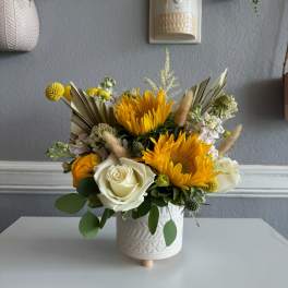 Yellow and white floral arrangement in a white ceramic pot