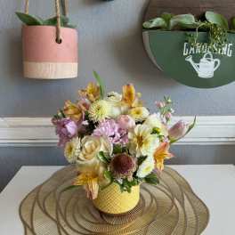 Pastel mixed flower arrangement in a yellow textured pot