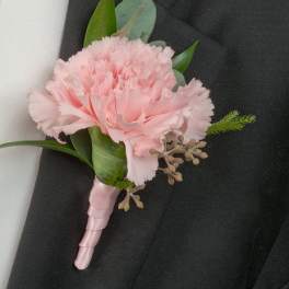 Pink carnation boutonniere with greenery on a black suit lapel