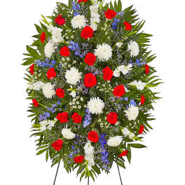 Standing floral spray with red roses, white blooms, and blue accents